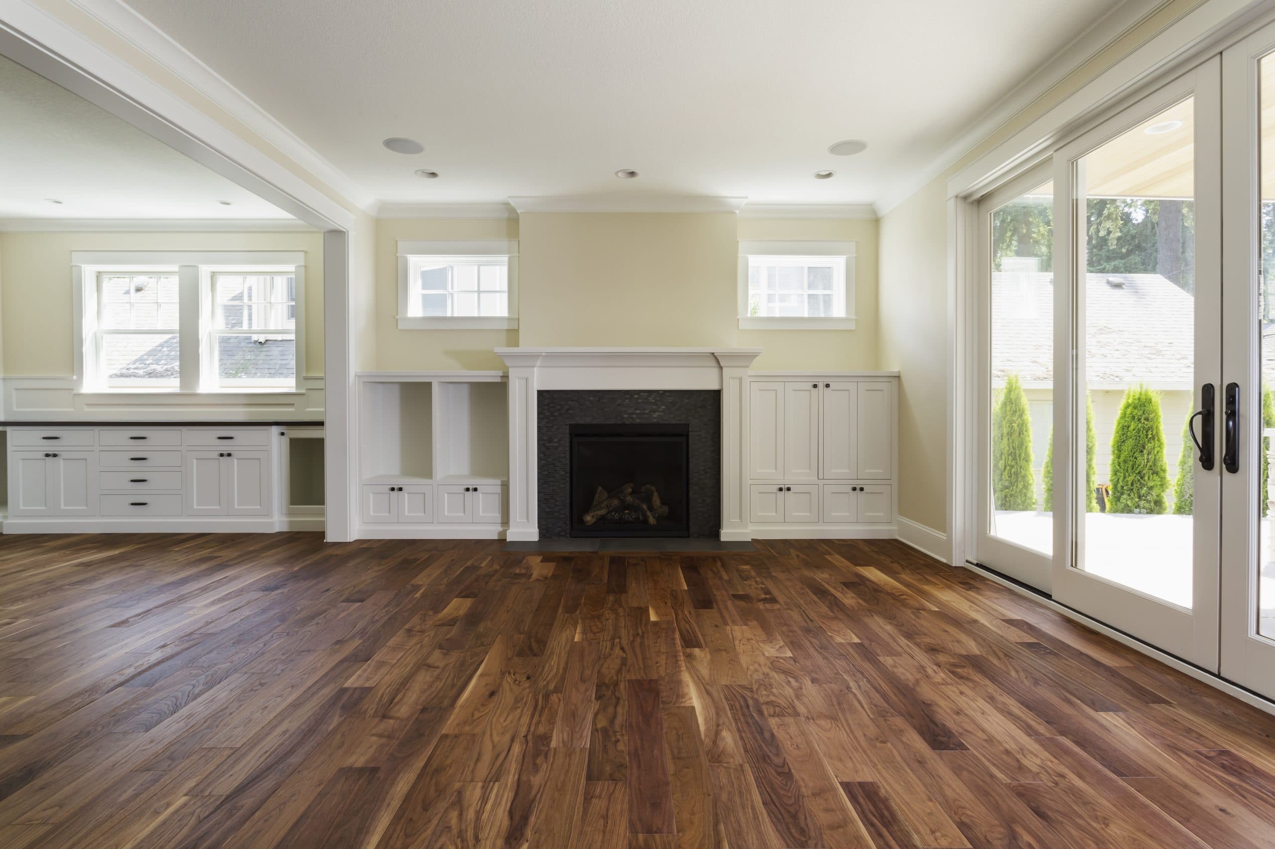 Open living area with wide-plank hardwood flooring running through to a bright window wall