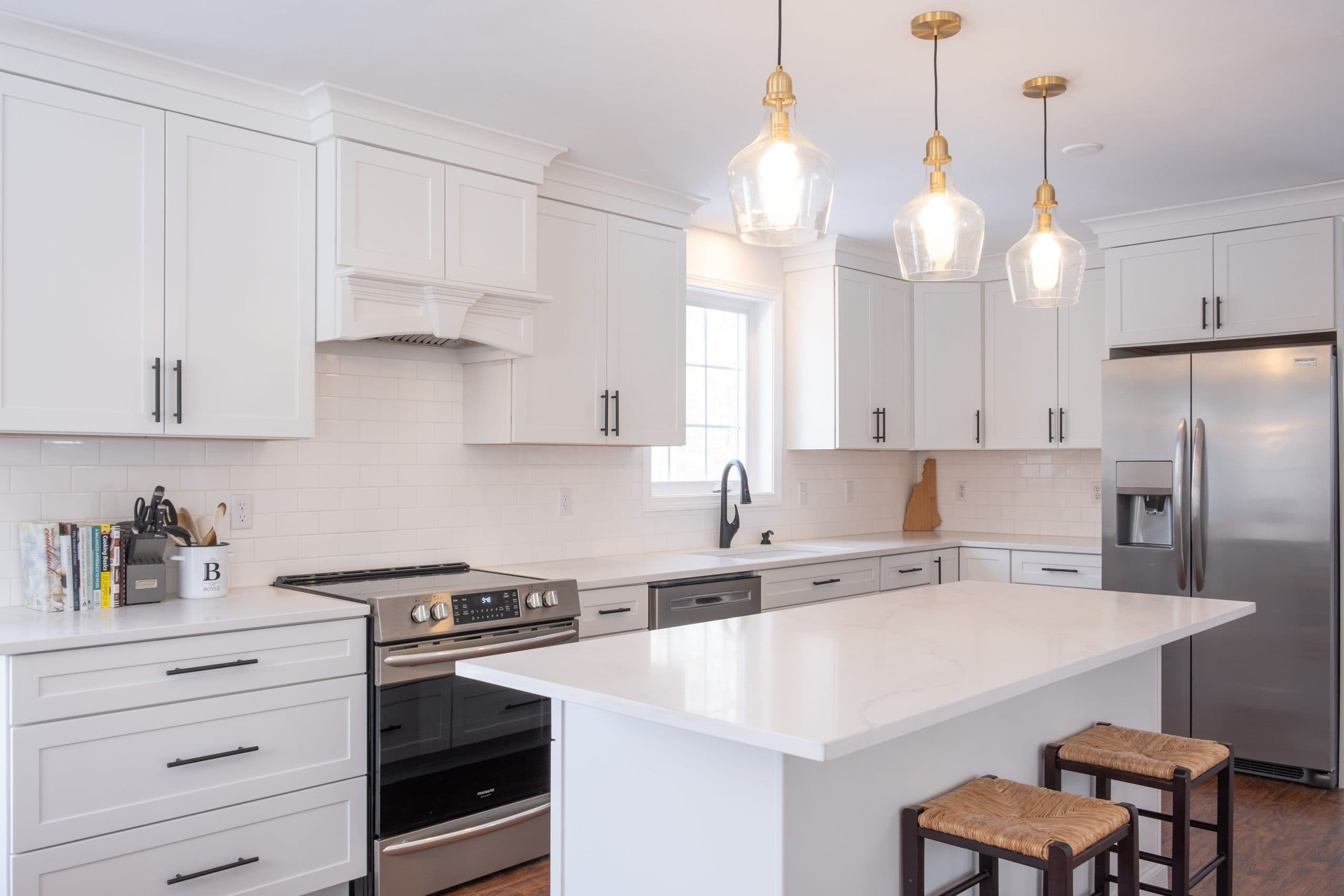 Remodeled kitchen with white shaker cabinetry, a stone-topped island and pendant lighting