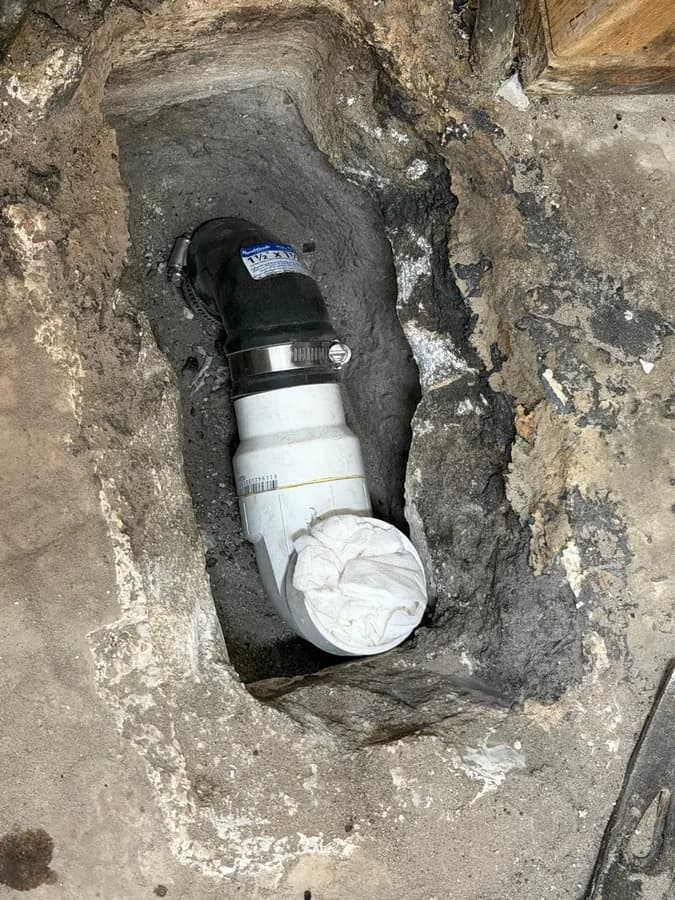 Shower drain rough-in exposed in the floor during a tub-to-shower conversion