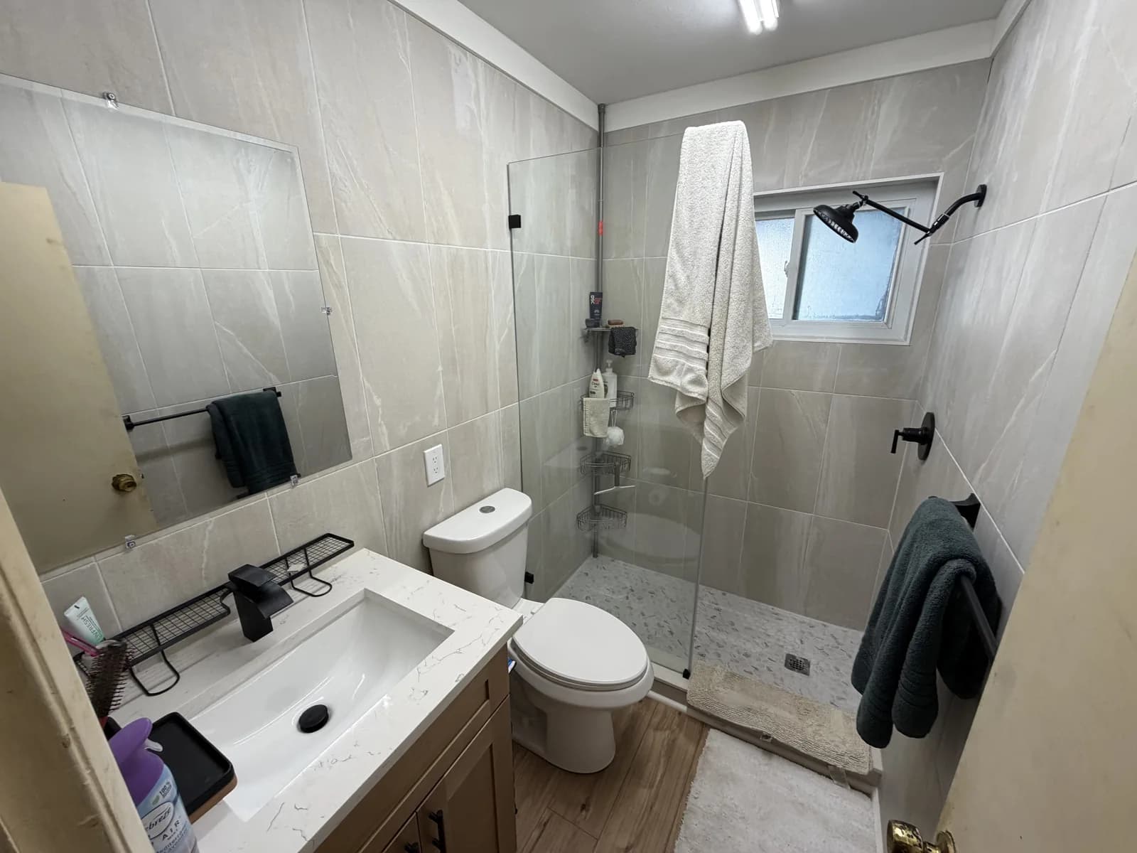 Bathroom where a bathtub has been replaced with a tiled walk-in shower and glass panel