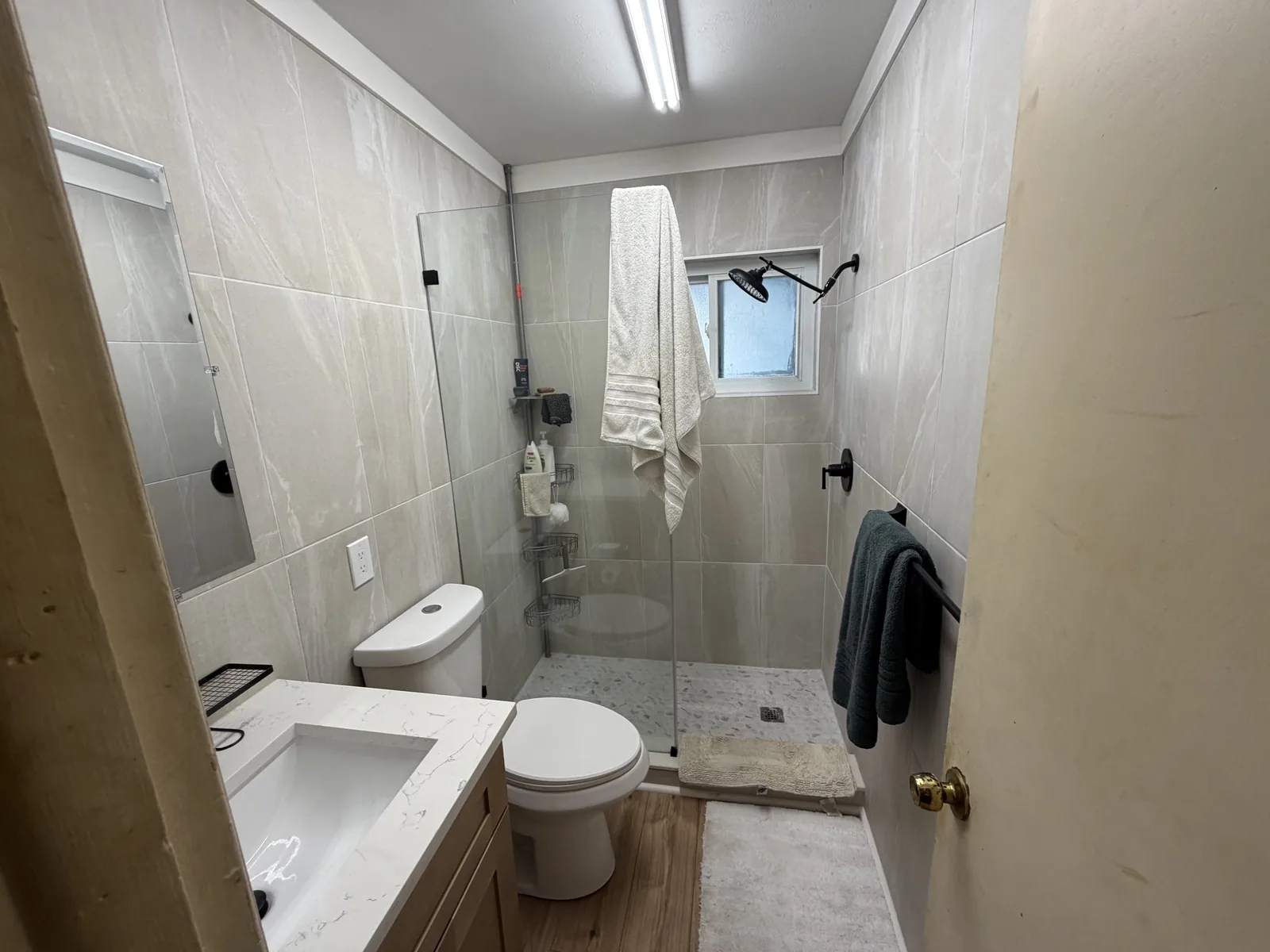 Bathroom vanity with a white top, wood cabinet base and black tapware below a framed mirror