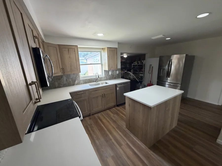 Close-up of a white quartz countertop edge above wood cabinetry, with an undermount sink