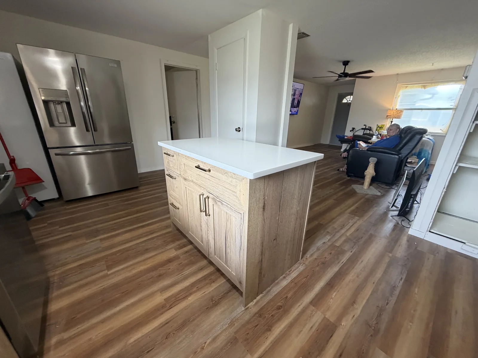 Remodeled kitchen with natural wood shaker cabinets, white quartz countertops and a wood-look plank floor